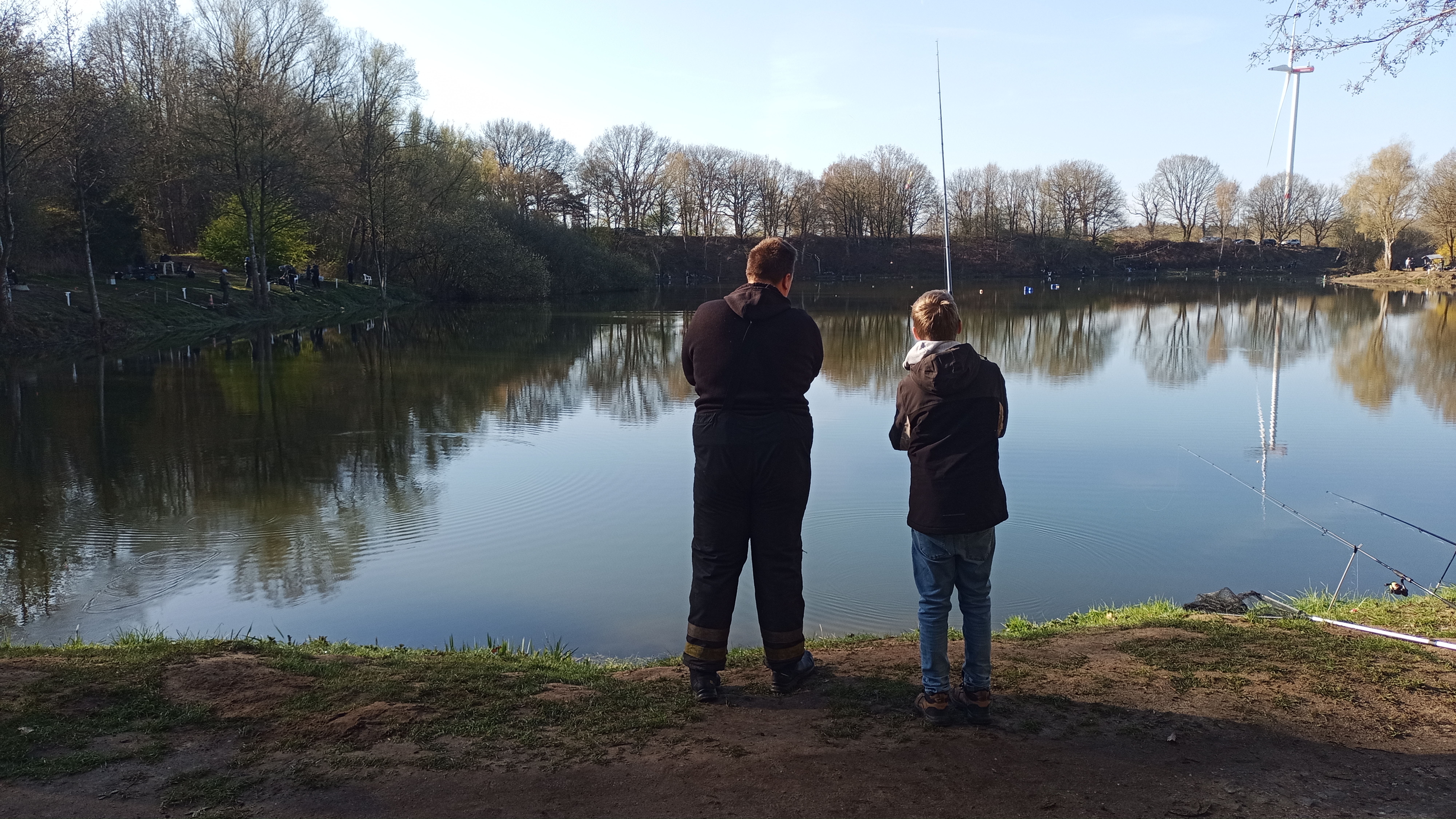 Forellensee mit jugendlichen Angler, ein Erwachsener steht daneben